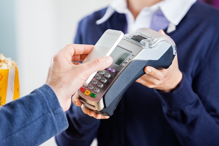 ropped image of man using nfc technology to pay bill at cinema