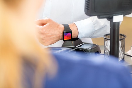 midsection of male customer paying through smartwatch in pharmacy