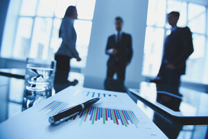 Close-up of business objects at workplace on background of office workers interacting