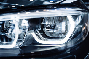 Luminous car headlight. Macro photo of automobile exterior detail as industrial and technological design.