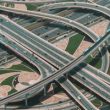 A high angle shot of a big highway with multiple roads and a train riding through the central road