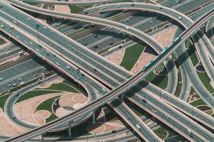 A high angle shot of a big highway with multiple roads and a train riding through the central road