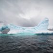An iceberg in the sea under a cloudy sky in Antarctica