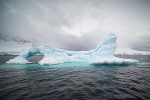 An iceberg in the sea under a cloudy sky in Antarctica