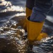 person in blue denim jeans and yellow boots standing on water