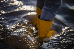 person in blue denim jeans and yellow boots standing on water