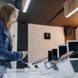 young attractive girl in electronics store stands at desk and tests phone. phones shop. concept of buying gadgets.