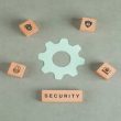 Conceptual of security with wooden blocks, paper settings icon on sage color background flat lay. horizontal image