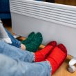 Two people warming up their feet at a heating system