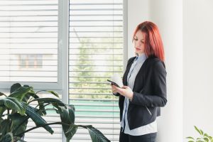 A woman standing near a window with blinds