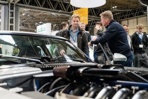 Two individuals standing with a electric vehicle