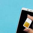 A SIM card held over a phone