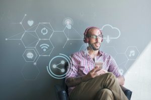 A man sitting with headphones on listening to something on his phone
