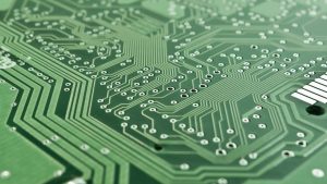 Close-up of a printed circuit board showing microchips and soldered connections, representing a chip-level secure element providing a hardware root of trust in IoT devices